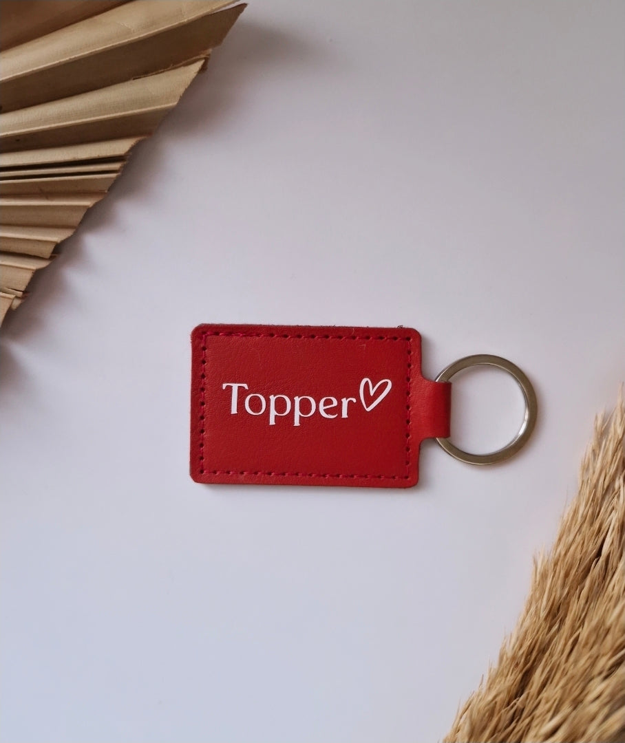 Rode lederlook sleutelhanger met wit opschrift Topper en een hartje