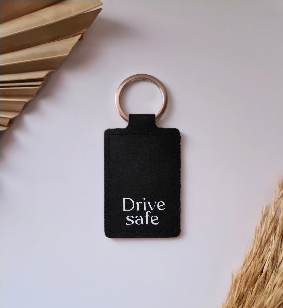 Zwarte lederlook sleutelhanger met wit opschrift drive safe